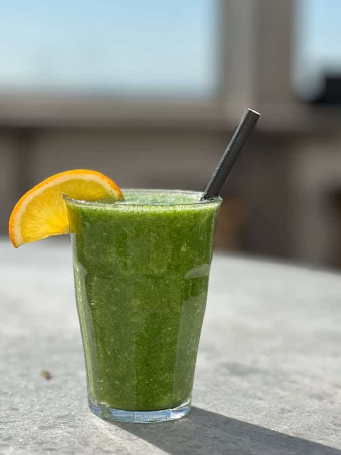 Fresh green smoothie with lemon wedge, promoting healthy lifestyle choices and wellness.